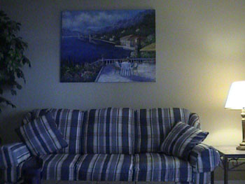 Blue striped couch with oil painting of lakeside village hanging above